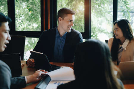 Multiracial business people gather to discuss the companys market plan for the coming year. Teamwork Togetherness Unity Concept.の写真素材