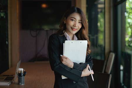 Image of beautiful business woman holds data document at work placeの写真素材