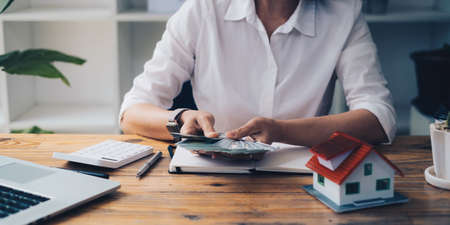 Business woman or broker checking money after contract agreement paper with customer to sign contract. Real Estate and Agreement concept.の写真素材