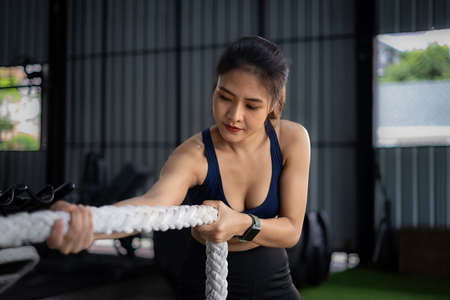 Female working out with battling rope at gym. Healthy modern people concept.の写真素材