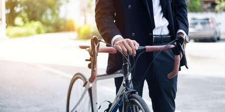 Handsome young asian businessman in suit have smiling with bicycle go to work at morningの写真素材