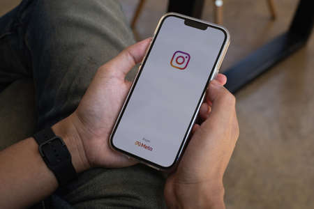 CHIANG MAI, THAILAND - NOV 07, 2021: A man hand holding iphone with logo of instagram from meta. Instagram reels for making short videos and storyのeditorial素材