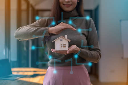A real estate agent demonstrates the House model to clients interested in purchasing house insurance. The concept of home insurance and property.の写真素材