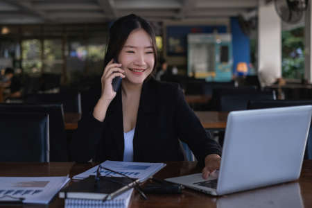 When she receives positive news from a customer, the happy businesswoman converses with her partners by cell phone.の写真素材