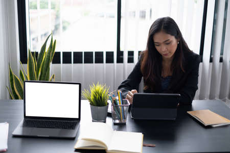 Portrait of cheerful asian woman with casual life on desk in home office. Concept of young business people working at home.の写真素材