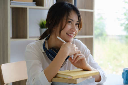 Portrait of cheerful asian woman with casual life on desk in home office. Concept of young business people working at homeの写真素材