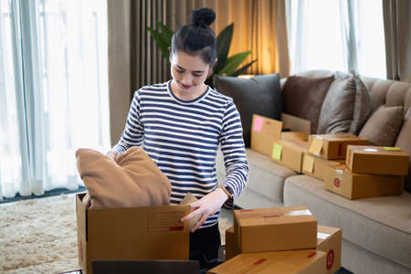Asian small business owner checking order by smartphone at home office. Business retail market and online sell marketing delivery, SME e-commerce conceptの写真素材