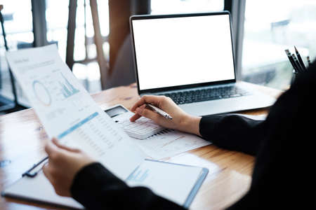 Business woman or Accountant hand holding pen and using calculator to analyze company budget,...