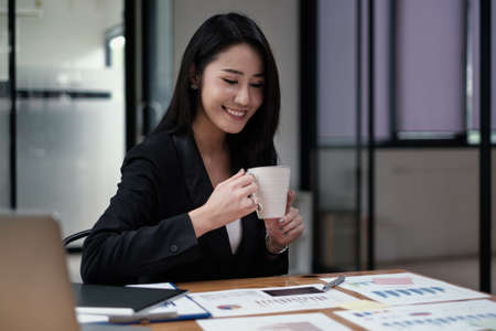 Businesswoman or Accountant holding coffee and audit the companys budget. Tax information is calculated by accountantsの写真素材