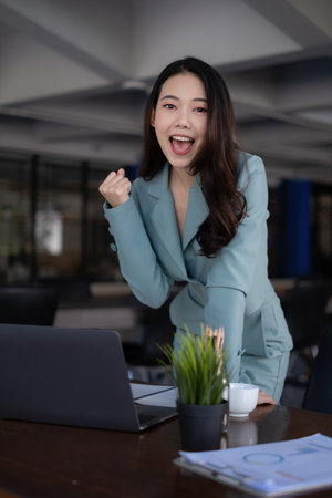 Excited asian business woman and celebrating success and video call with her business team. Finance, tax, fund, account concept.の写真素材
