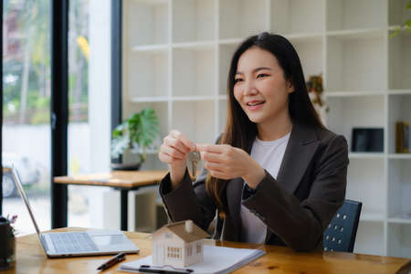 Business woman or Agent giving house key after signing agreement for buying house. Bank manager and real estate concept.の写真素材