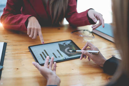 Two Businesswoman data analyzing technology by digital tablet software for investment decision...