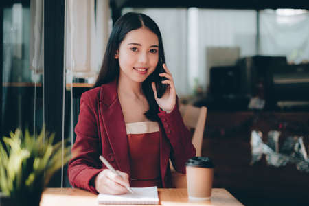 Photo of gorgeous secretary working at cafe. she sitting at the wooden desk. Accountant, fianance conceptの写真素材