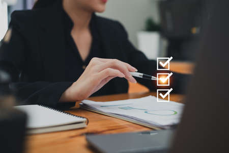 Close up Business woman hand holding pen and selecting the best insurance and saving money plan.の写真素材