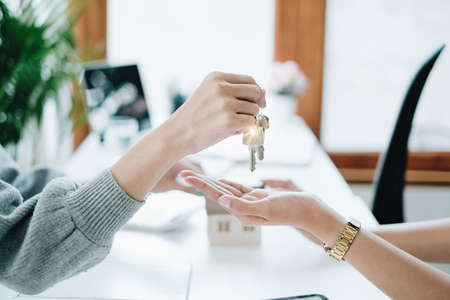 Close up of Business woman giving house key after signing agreement for buying house. Bank manager and real estate conceptの写真素材