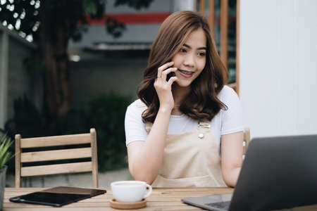 Young Asian student talking with friend by mobile phone outdoor park.の写真素材