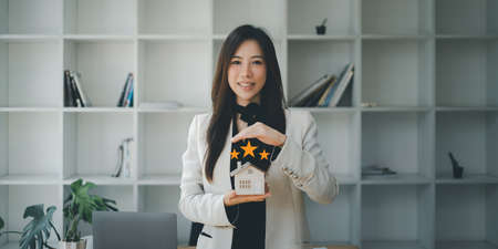 Asian insurance agent making hand symbol to protect house from accident. Real Estate and Agreement...