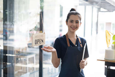 Portrait of asian woman barista cafe owner smile while cafe open. SME entrepreneur seller business concept.の写真素材