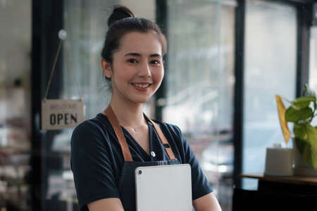 Portrait of asian woman barista cafe owner smile while cafe open. SME entrepreneur seller business concept.の写真素材