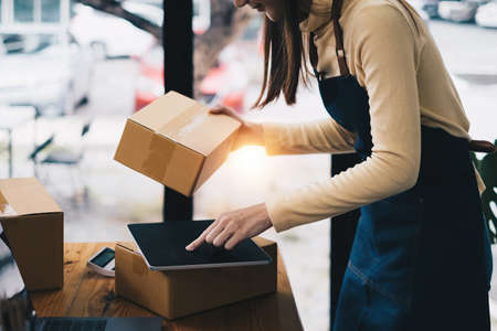 Business owner confirm address to send to customer orders talking by digital tablet before pack products. Successful SME entrepreneur concept.の写真素材