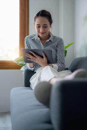 Woman enjoy with content social media application on digital tablet lay down on sofa at home