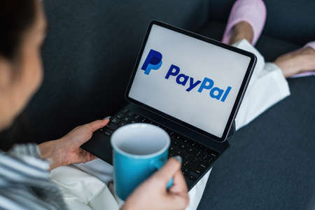 CHIANG MAI, THAILAND - MAR 18 2021 : Woman using Ipad with paypal logo on screen. PayPal is a...