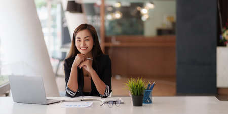 Business woman hand holding pen looking at bank savings account application on laptop. account or...
