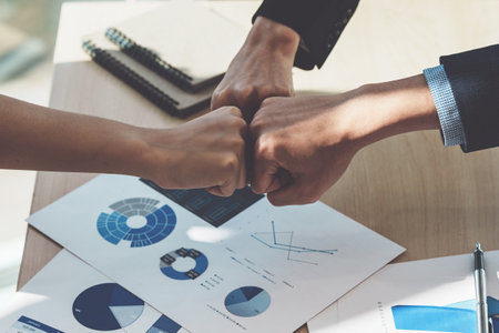 Asian business people give each other show hand of success symbol as they celebrate a successful team building project.の写真素材