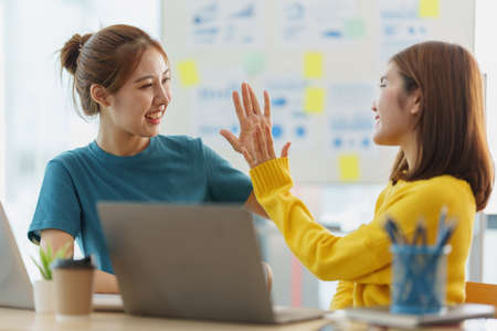 Asian business people give each other show hand of success symbol as they celebrate a successful team building project.の写真素材