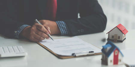 Close up of Business man pointing and signing agreement for buying house. Bank manager concept.の写真素材