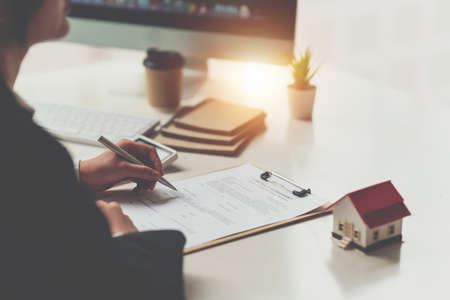Close up of Business woman pointing and signing agreement for buying house. Bank manager concept.