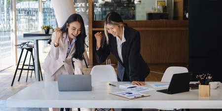 Asian business people give each other show hand of success symbol as they celebrate a successful team building project.の写真素材
