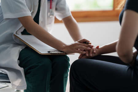 Doctor hold hand of patient and giving consolation and consultation at clinic.の写真素材