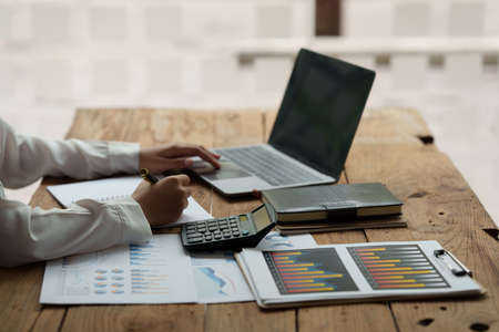 Close up Business woman hand using calculator to calculate the companys financial results and...