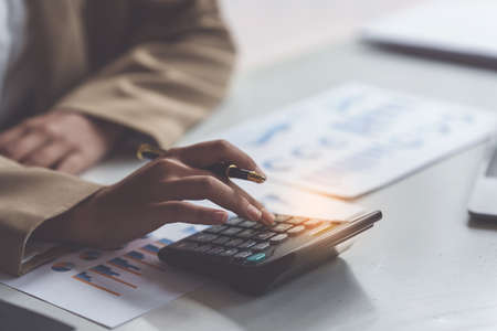 Close up Business woman hand using calculator to calculate the companys financial results and...