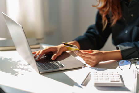 Woman using shopping web site by laptop computer and payment by credit card.