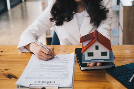 Close up of Business woman pointing and signing agreement for buying house. Bank manager concept.の写真素材