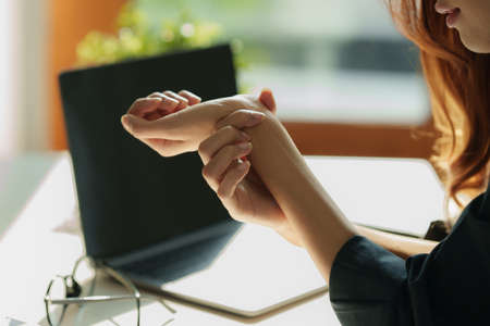 Asian Business woman holding her wrist pain from overworking. Office syndrome.の写真素材
