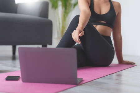 Young woman practicing yoga follow teacher in laptop online class at home. Calmness and relax concept.の写真素材