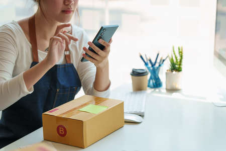 Asian small business owner with packing parcel box at home office, SME e commerce concept.の写真素材