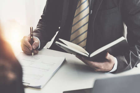 Business woman and lawyers discussing contract papers with brass scale on wooden desk in office....