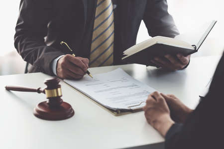 Business woman and lawyers discussing contract papers with brass scale on wooden desk in office....