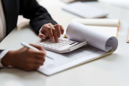 Consult financial concept. Business woman pointing at paperwork and using calculator.