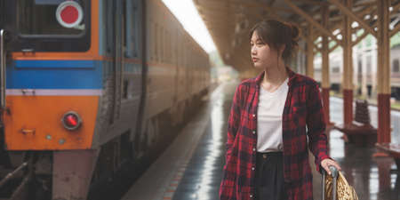 Happy Young traveler woman looking for friend planning trip at train station. Summer and travel lifestyle concept.の写真素材