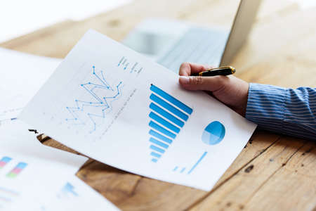 Asian Businessman working to analyze technical price graph and indicator with business team talking by cell phone. account or saving money or insurance concept.の写真素材