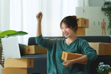 Online marketing packing box delivery concept. Asian Woman startup small business freelance with...