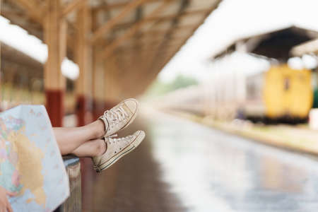 Young traveler woman looking on maps planning trip at train station. Summer and travel lifestyle...