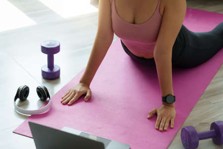 Young woman practicing yoga follow teacher in laptop online class at home. Calmness and relax...