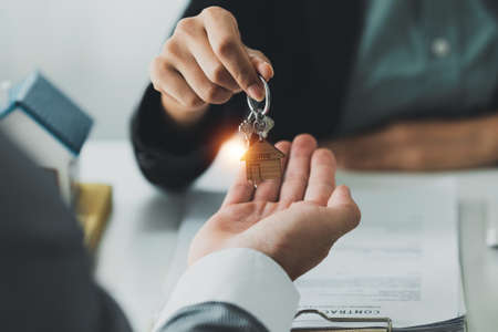 Close up Business woman or Real Estate agent giving house key after signing agreement for buying...