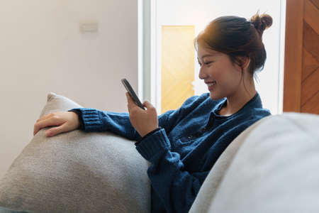 Portrait of Young Asian woman chatting with her friend by smartphone sitting on floor at bedroom....